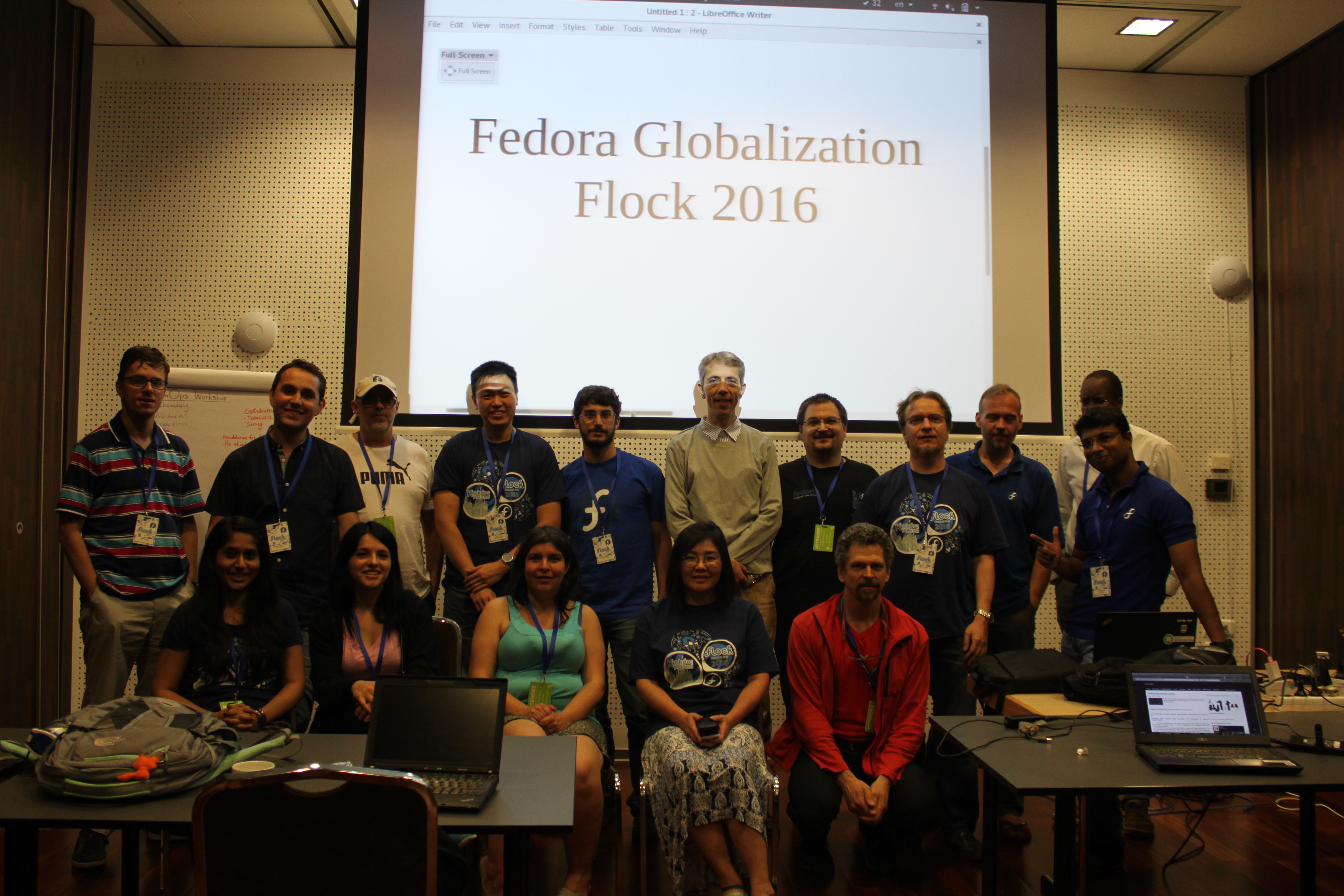 Một nhóm khoảng 15 người đang đứng chụp ảnh trước màn chiếu, trên slide có dòng chữ 'fedora globalization flock 2016`